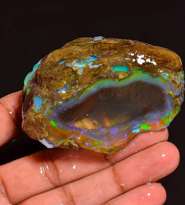 AAA+ Natural Ethiopian Fire Opal rough raw gemstone showing vivid green and red play of color - hand held close up