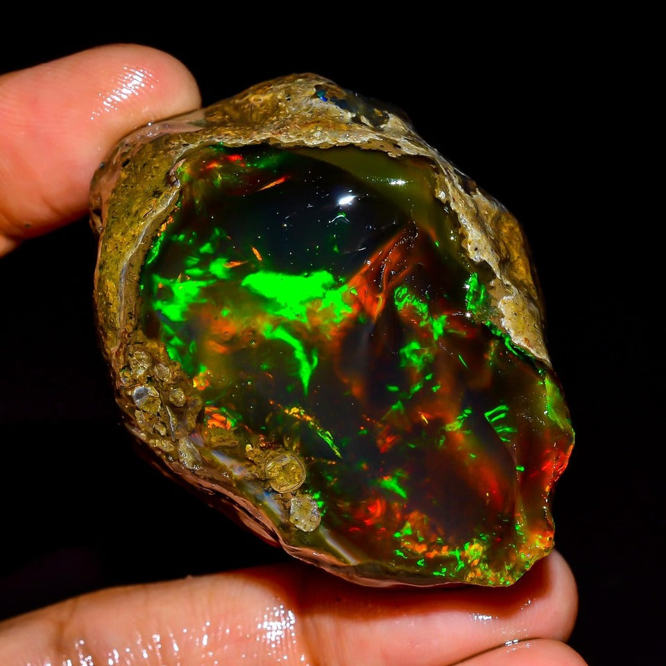 Natural Ethiopian Opal rough raw stone showing teal blue and rainbow iridescent play of color - palm view
