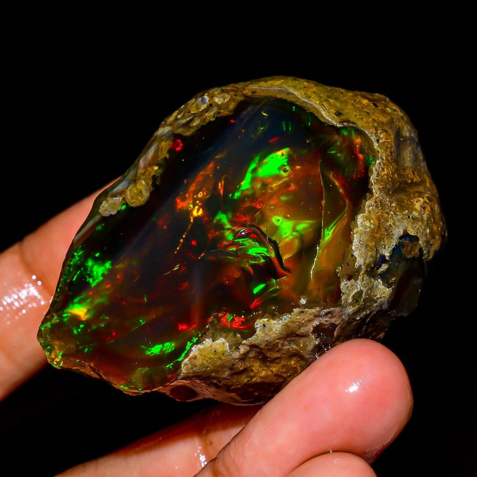 AAA+ Ethiopian Fire Opal rough raw gemstone with brilliant green and orange play of color - two-hand close up