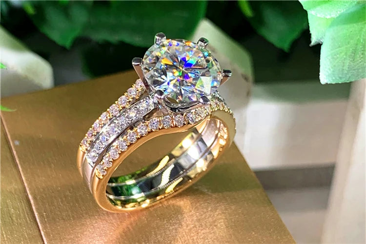 Gold ring with a large diamond and smaller diamonds on a reflective surface