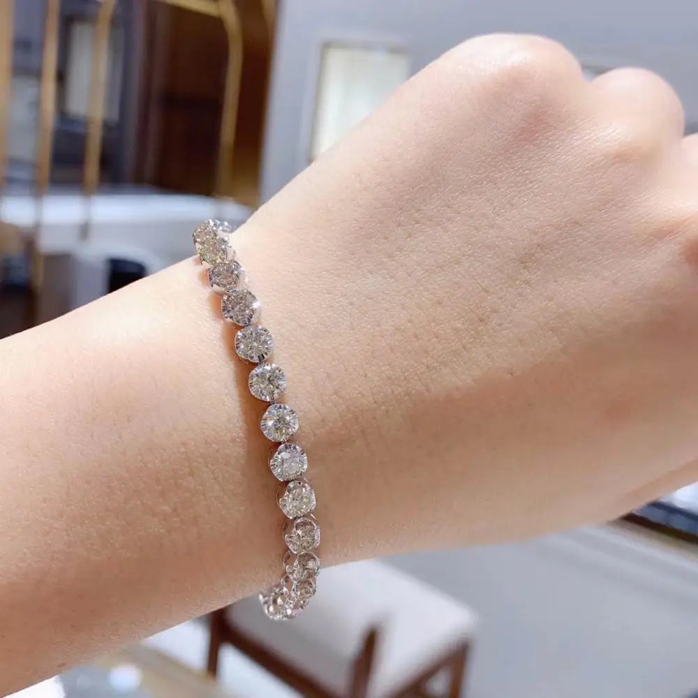 Close-up of a hand wearing a diamond bracelet with a blurred indoor background