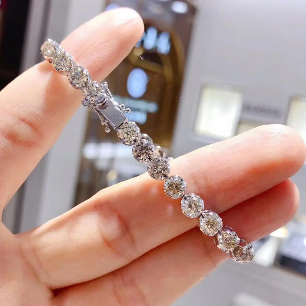 Silver bracelet with clear stones held by a hand against a blurred indoor background