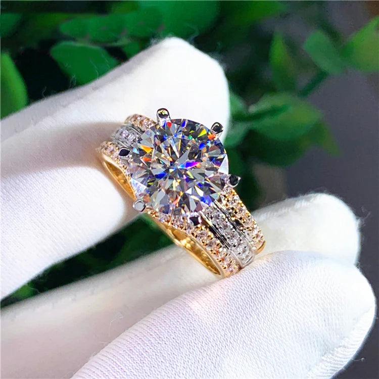 Gold ring with a large diamond on a white glove against a green leafy background
