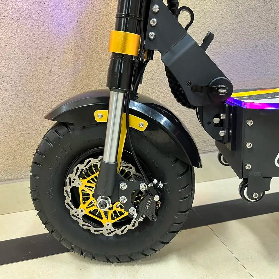 Close-up of a scooter wheel with black tire and yellow suspension fork against a neutral background