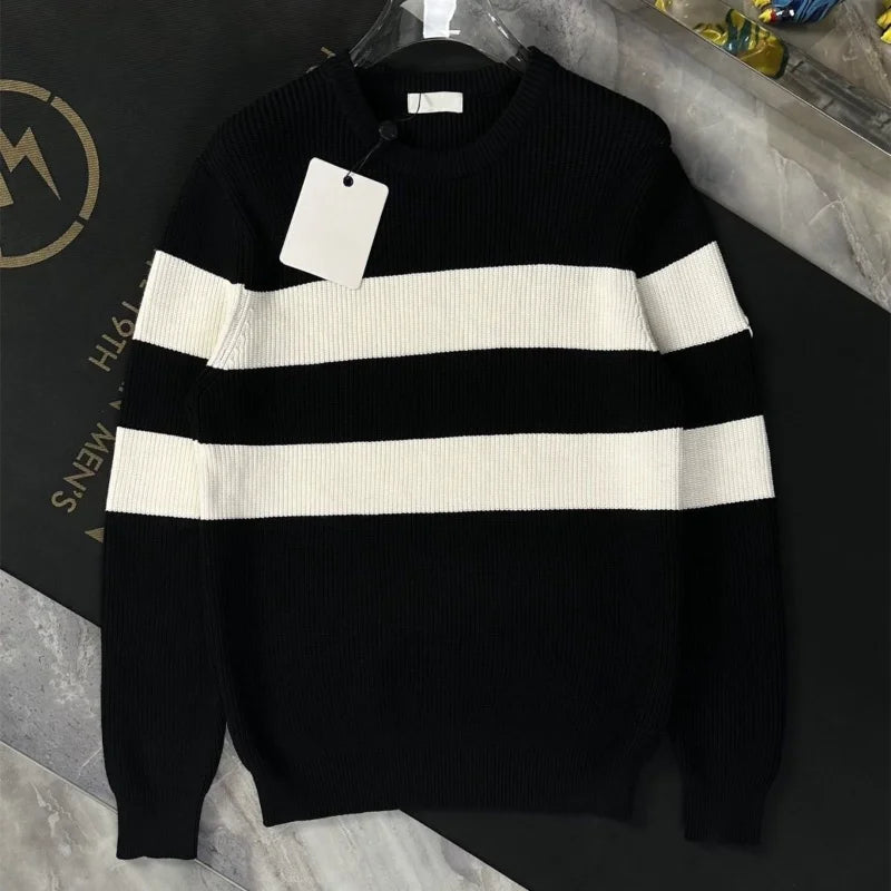 Black and white striped sweater on a hanger with a visible brand tag against a dark background.