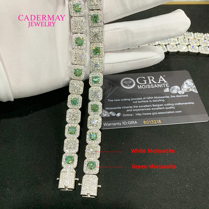 Jewelry display with green and white gemstones on a black surface, featuring CADERMAY JEWELRY branding.