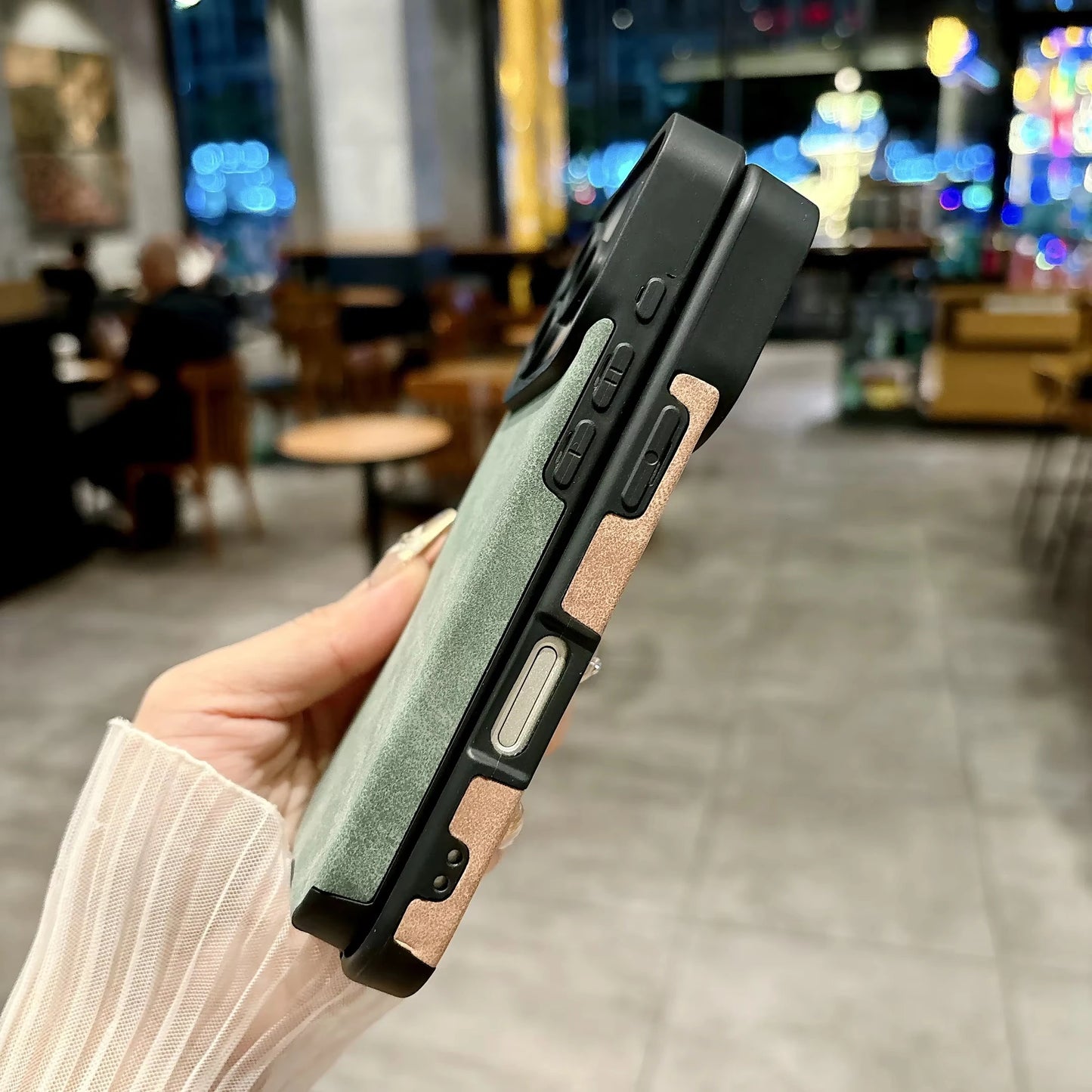 Hand holding a dual-tone phone case with a blurred indoor background