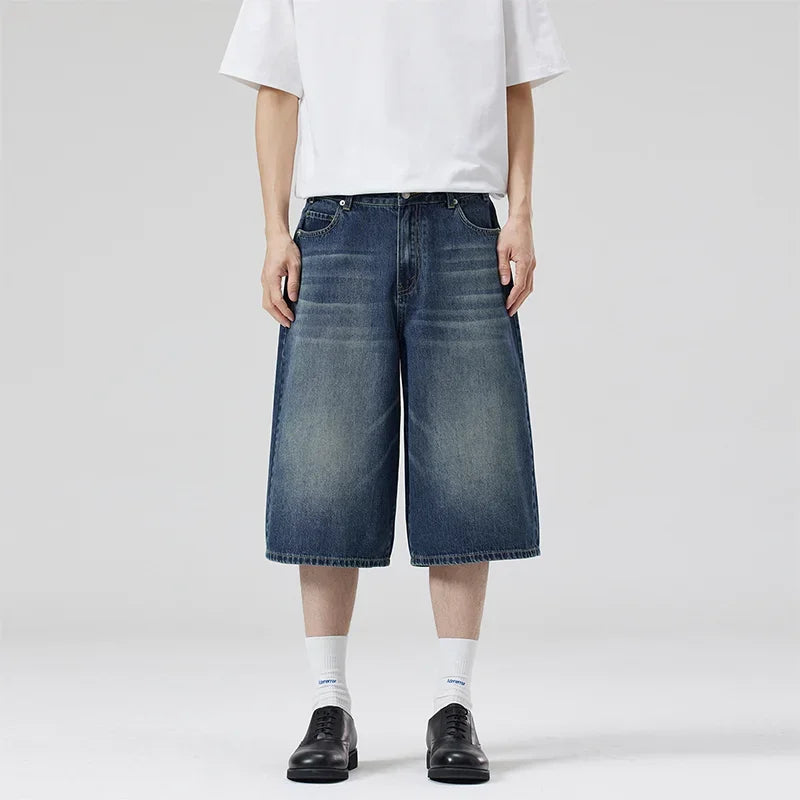 Person wearing blue denim shorts and a white t-shirt on a plain background