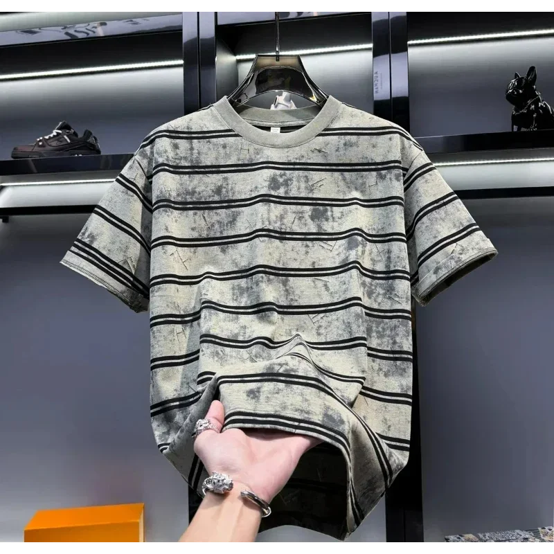 Striped t-shirt held by a hand with a blurred background