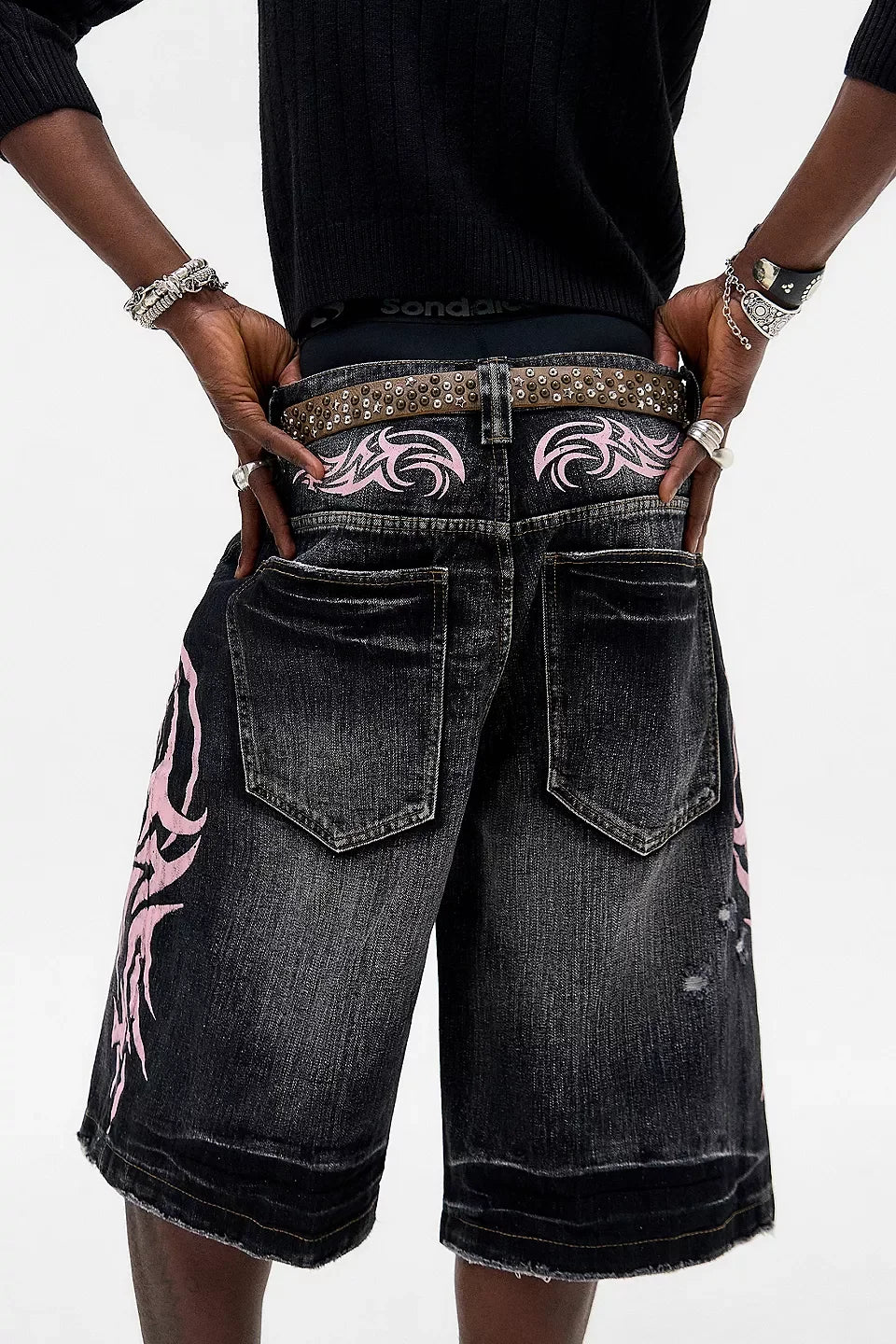 Black denim shorts with pink tribal designs on a white background