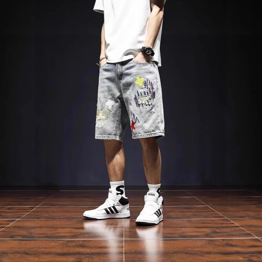 Person wearing gray shorts with colorful designs and white sneakers on a dark floor.