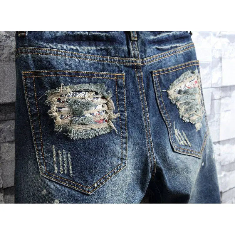 Close-up of blue jeans with distressed patches on a blurred background
