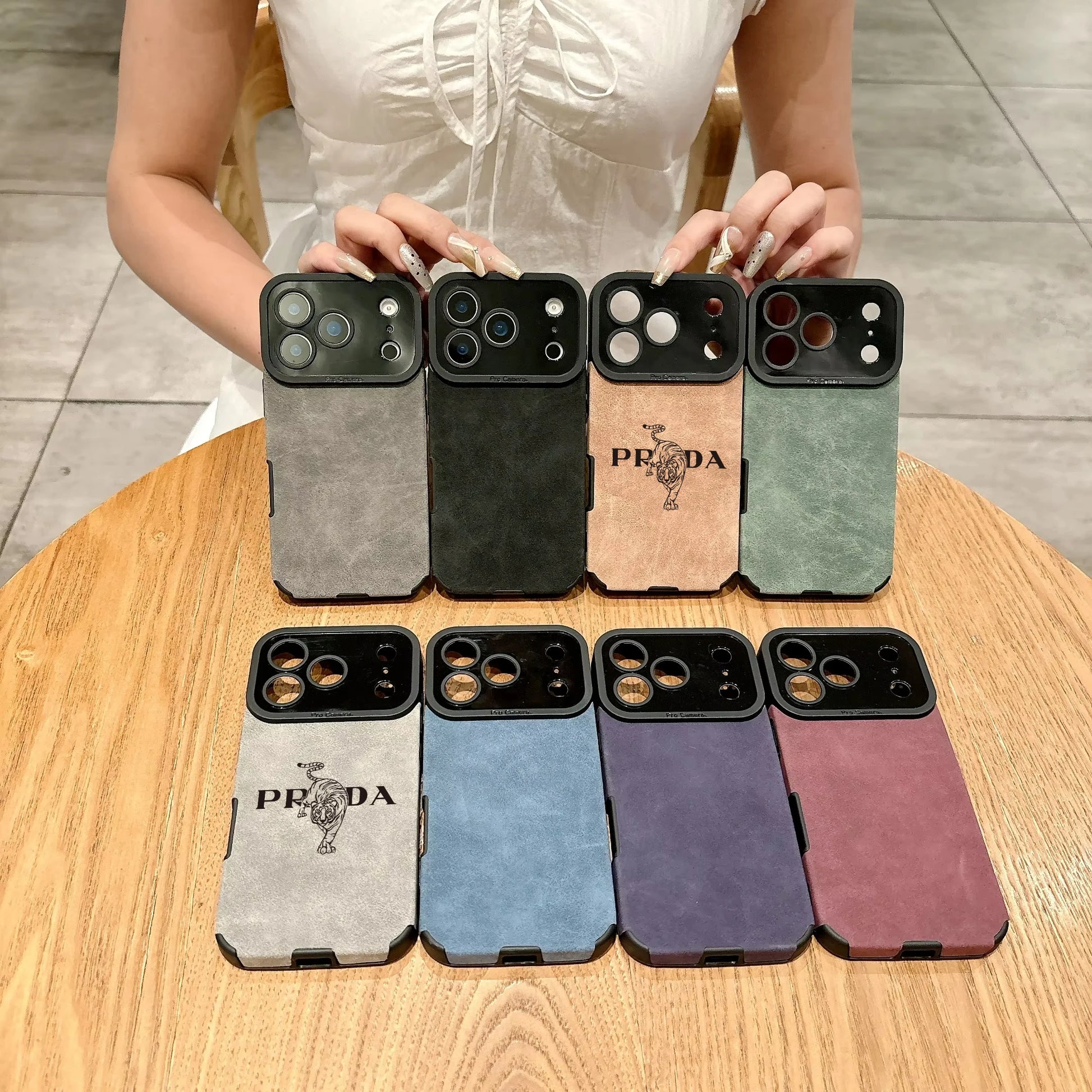 Collection of phone cases with Prada logo on a wooden table