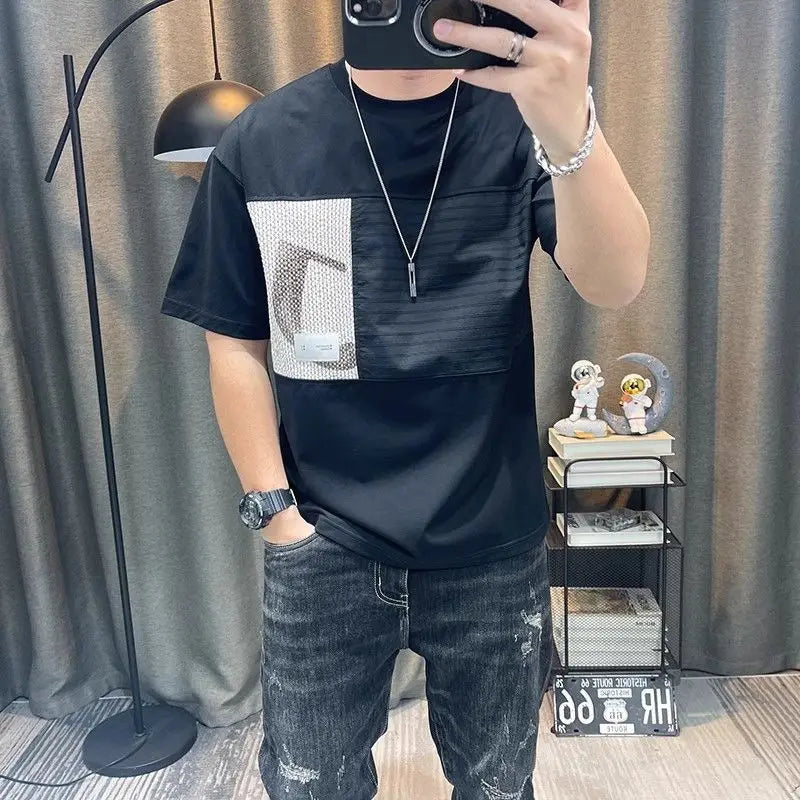 Person wearing a black t-shirt with a graphic design and jeans, taking a mirror selfie.