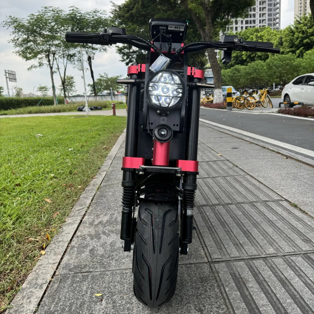 Black and red electric scooter on a sidewalk with greenery and buildings in the background