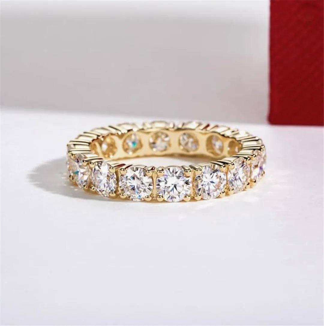 Gold ring with clear gemstones on a light background