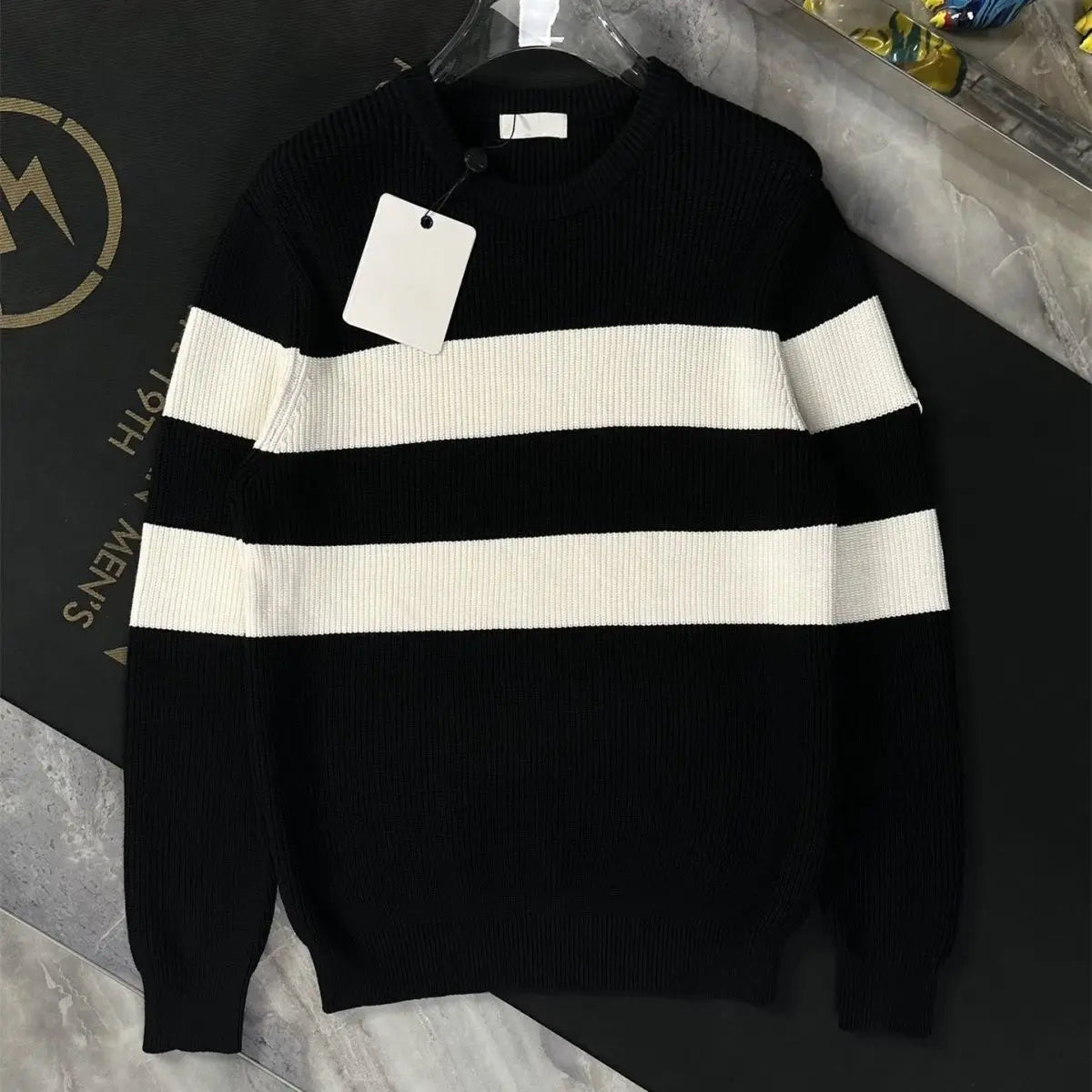 Black and white striped sweater on a hanger with a visible brand tag.
