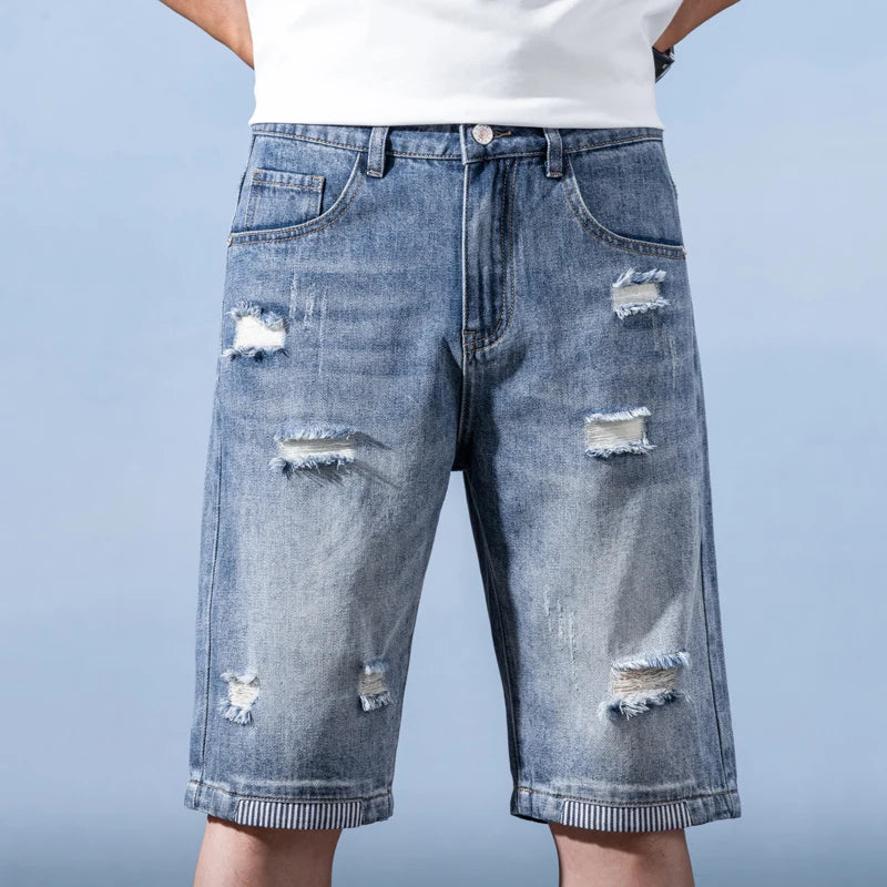 Distressed denim shorts worn by a person on a light blue background