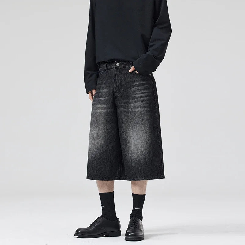 Person wearing black denim shorts and black shoes on a white background