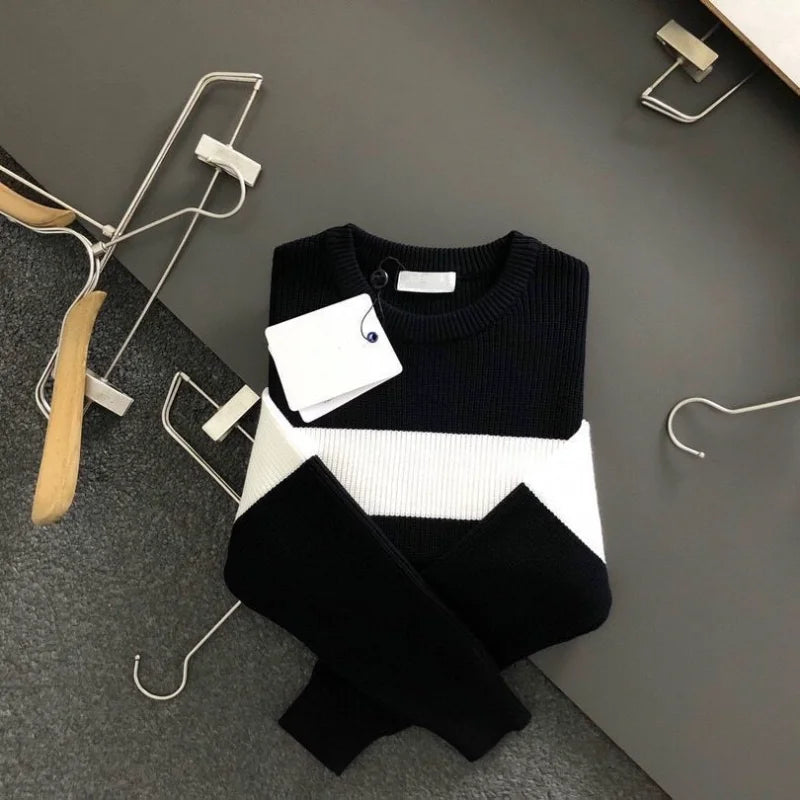 Black and white sweater on a gray surface with hangers around