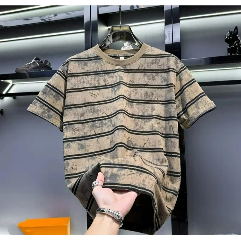 Striped t-shirt on a hanger with a hand holding it, against a blurred indoor background.