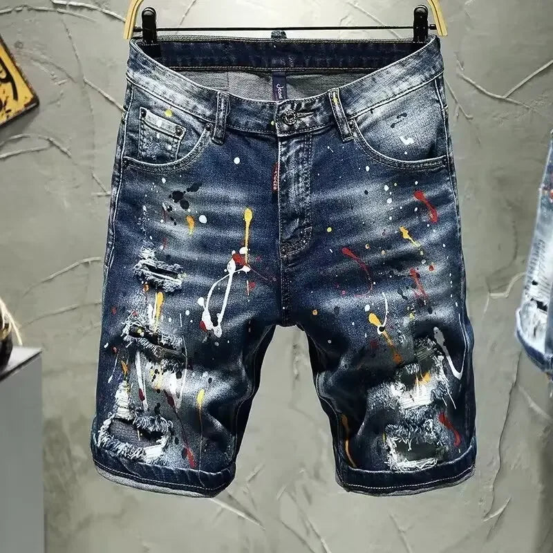 Blue denim shorts with artistic paint splatter design on a gray textured background