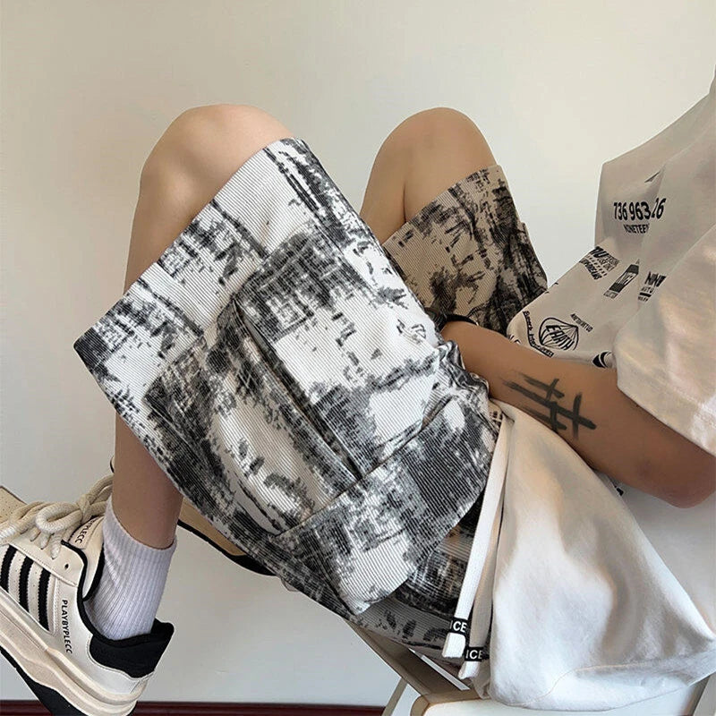 Person sitting with a black and white patterned bag and a white shirt with text.
