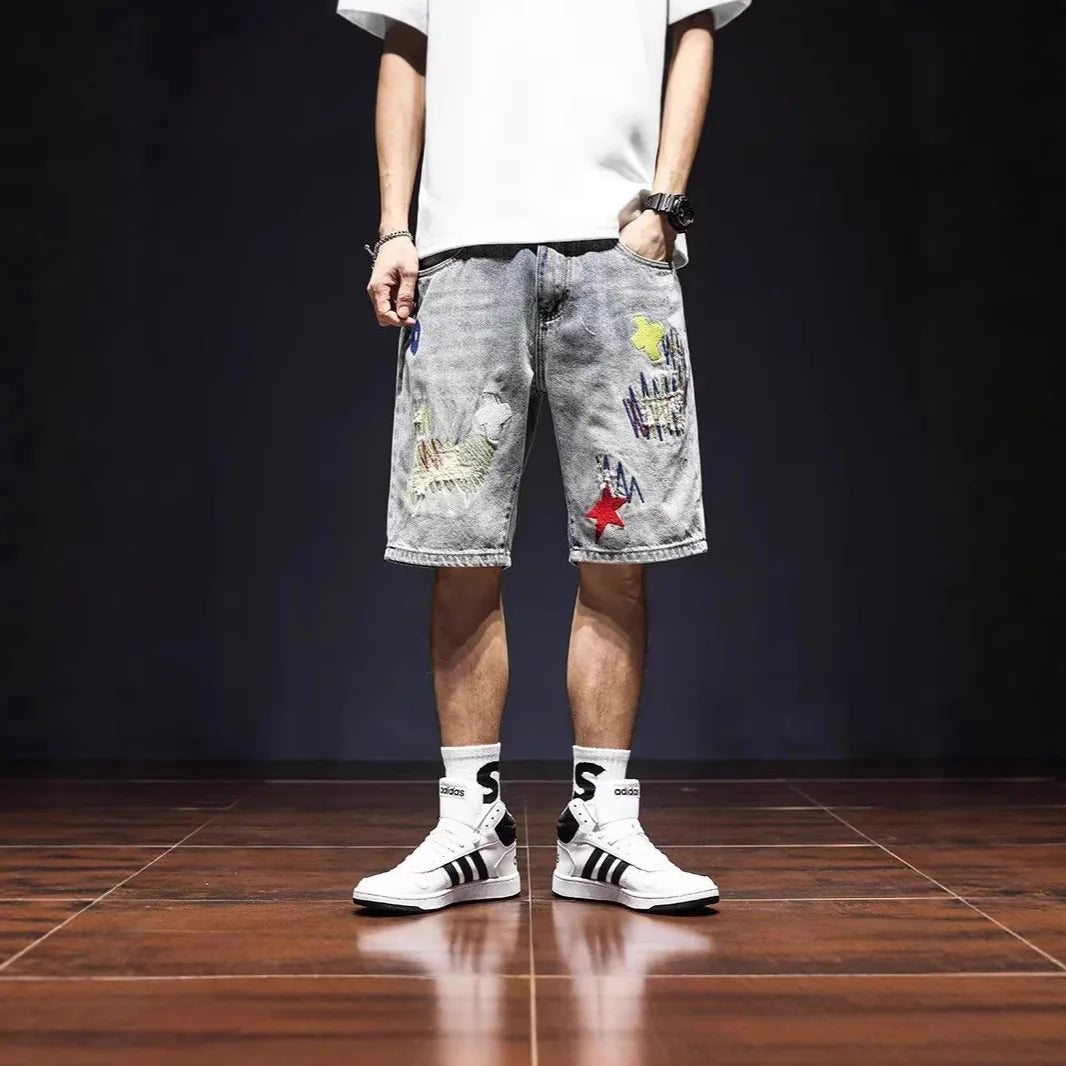 Person wearing gray shorts with colorful patches and white sneakers on a dark floor.
