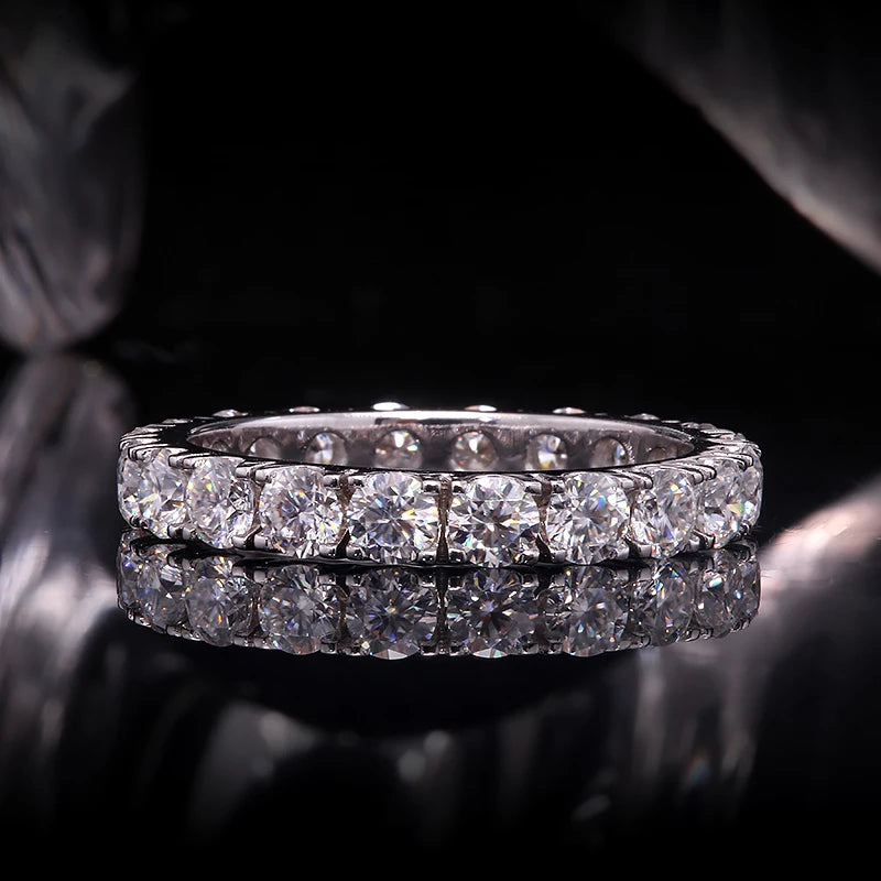 Diamond eternity ring on a reflective surface with a dark background
