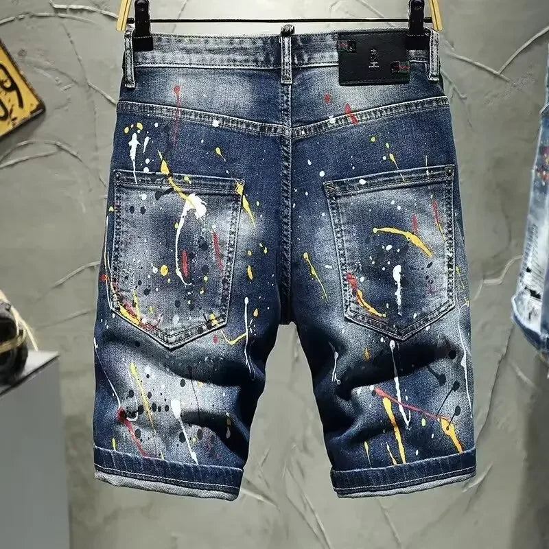 Blue denim shorts with colorful paint splatter design on a gray background