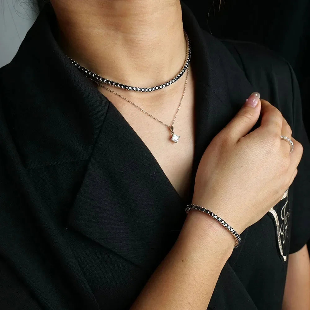 Person wearing multiple necklaces and a bracelet on a black background