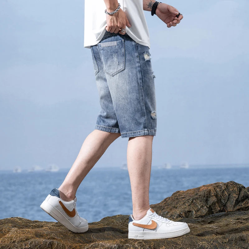 Person wearing light blue ripped denim shorts and white sneakers on a rocky surface with a blurred background