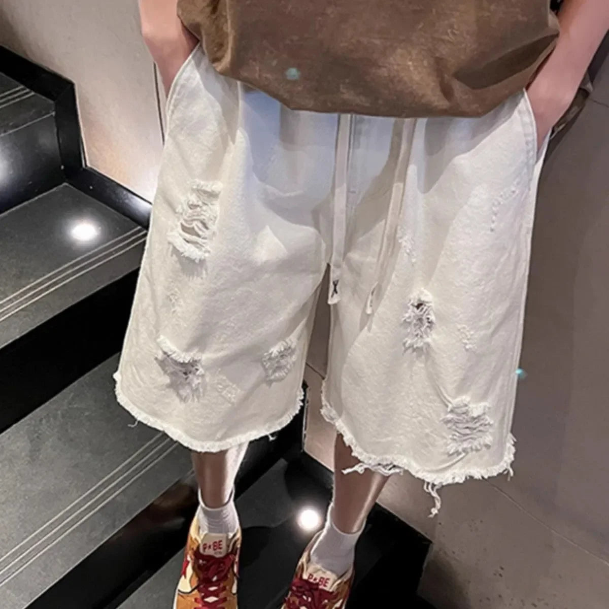 Person wearing white shorts with floral embellishments on a staircase.