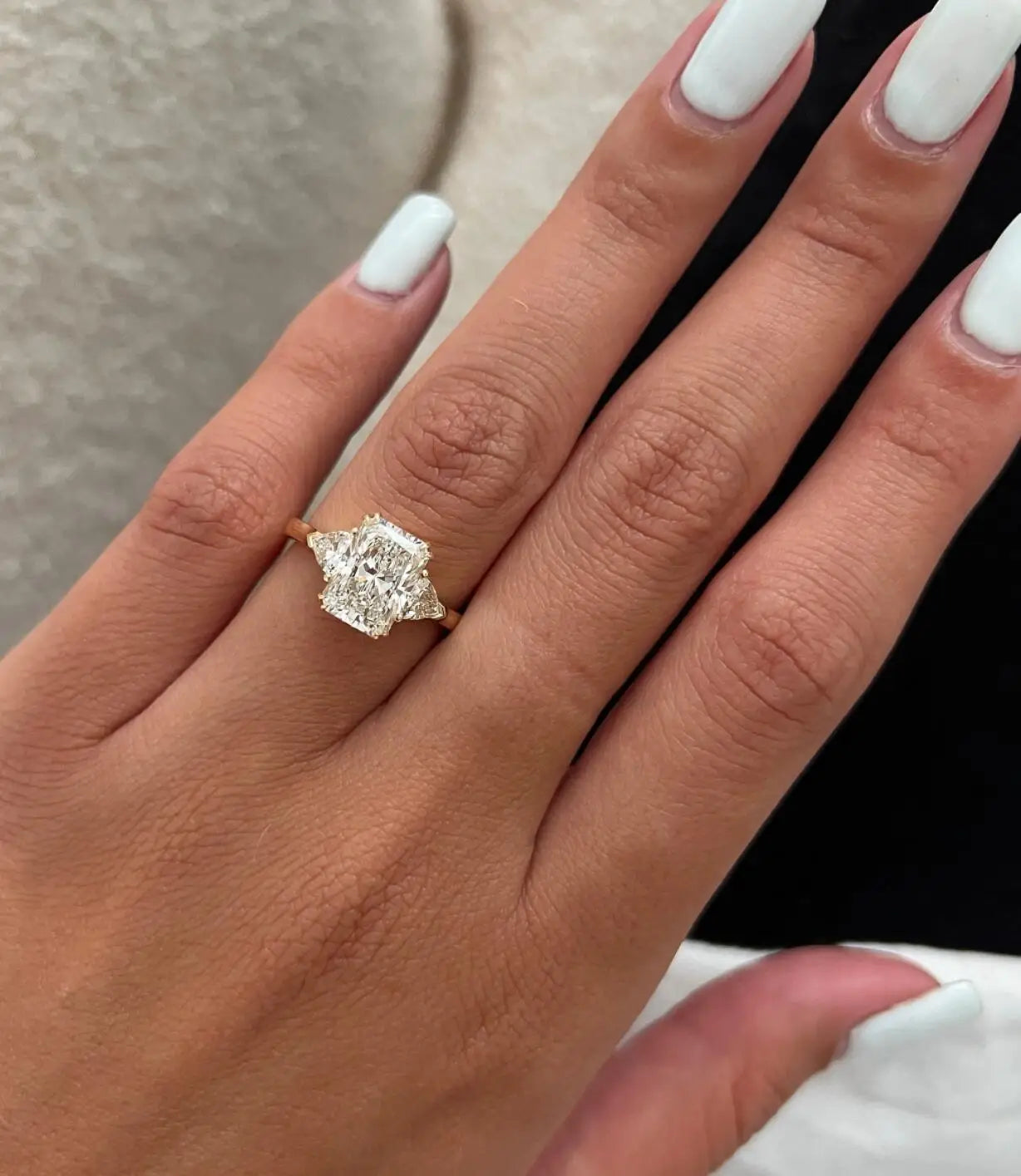Close-up of a hand wearing a diamond ring with a blurred background