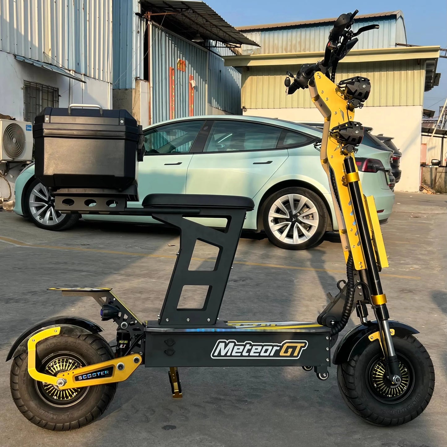 Yellow and black electric scooter with 'Meteor GT' branding in front of a car.
