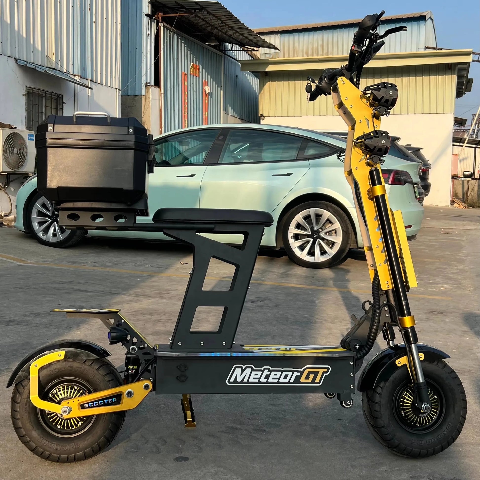 Yellow and black electric scooter with 'Meteor GT' branding in front of a car.
