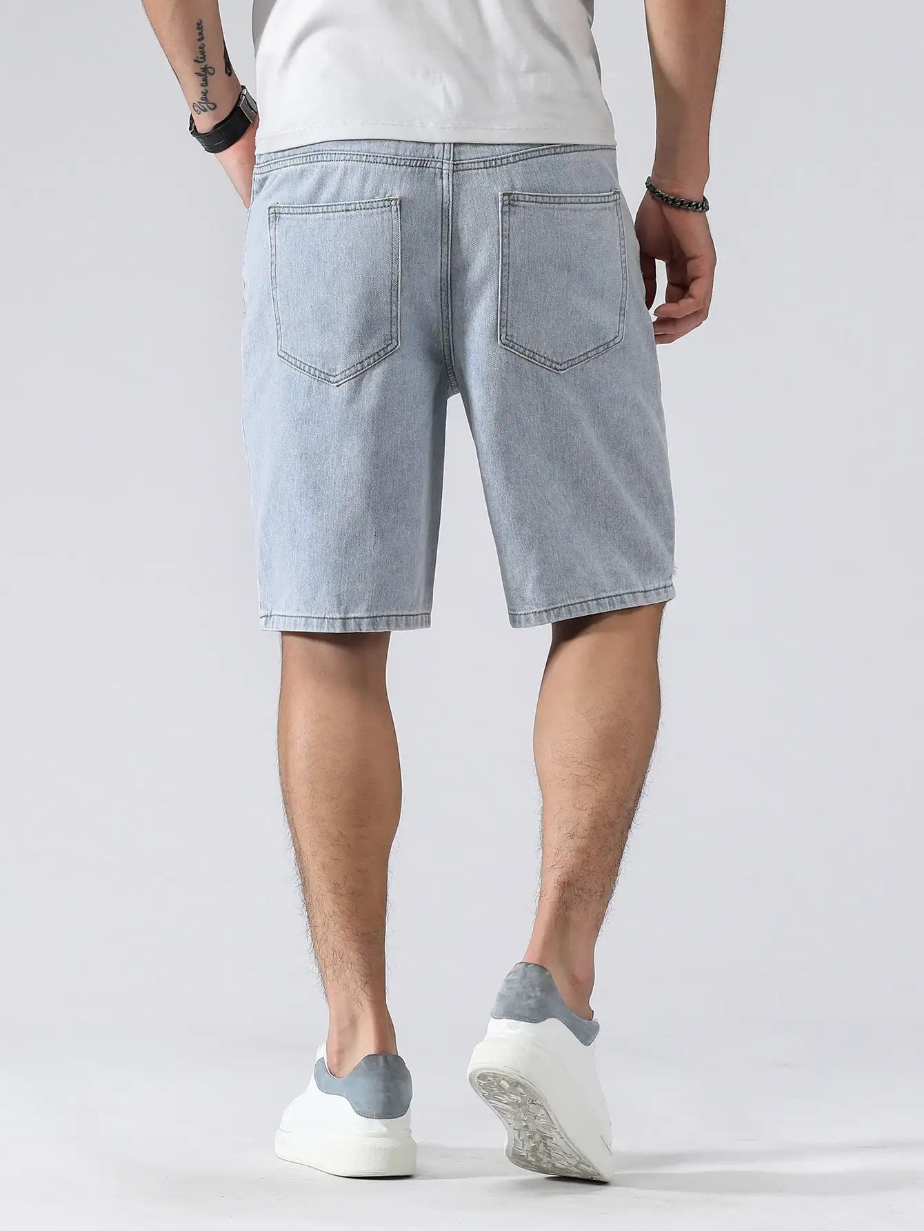Person wearing light blue denim shorts on a white background