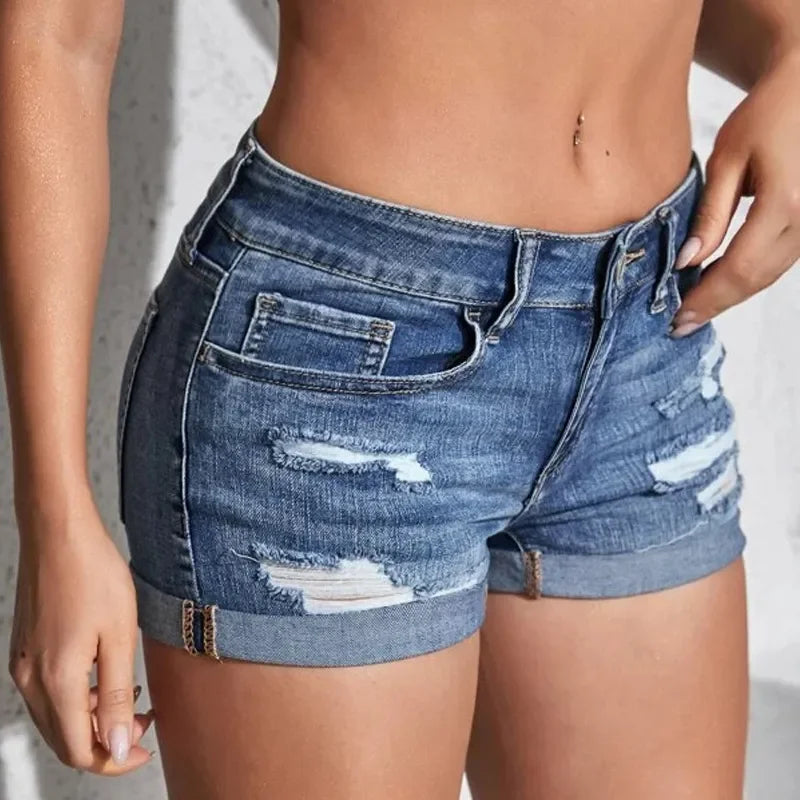Close-up of a person wearing distressed denim shorts against a neutral background