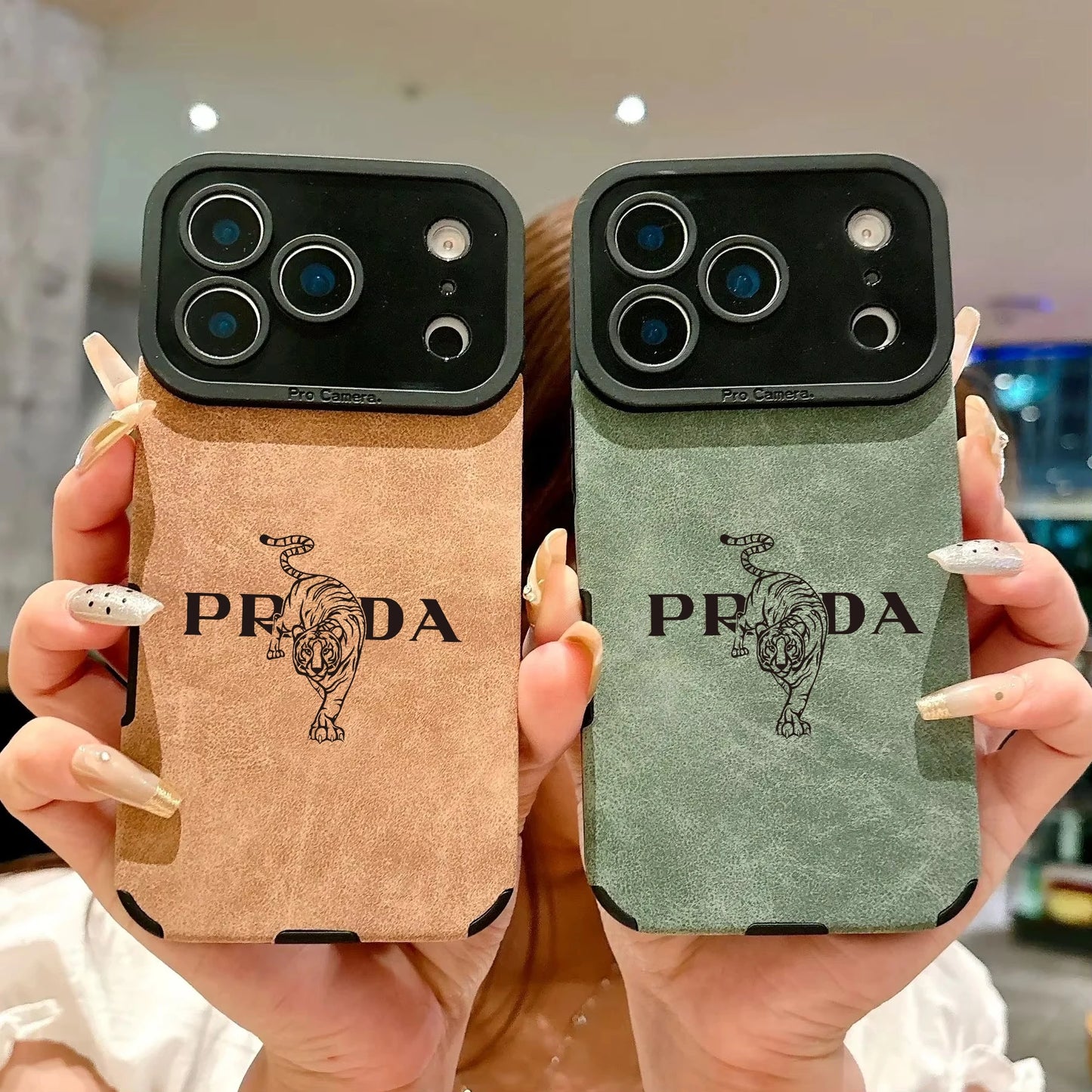 Two Prada phone cases held by a person with blurred background