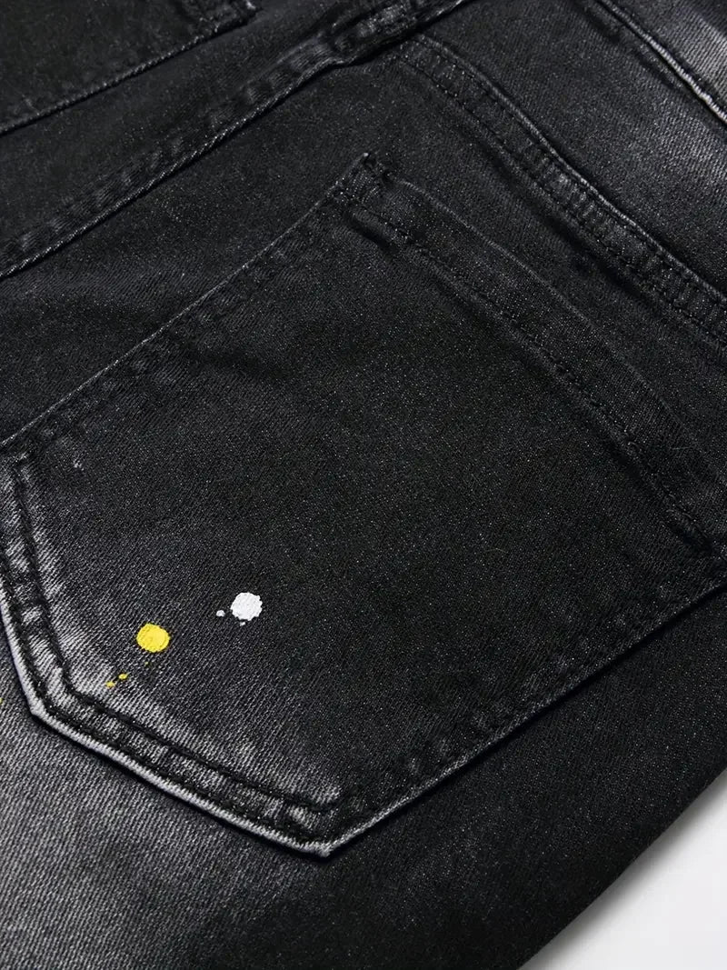 Close-up of a black denim pocket with paint splashes on a white background