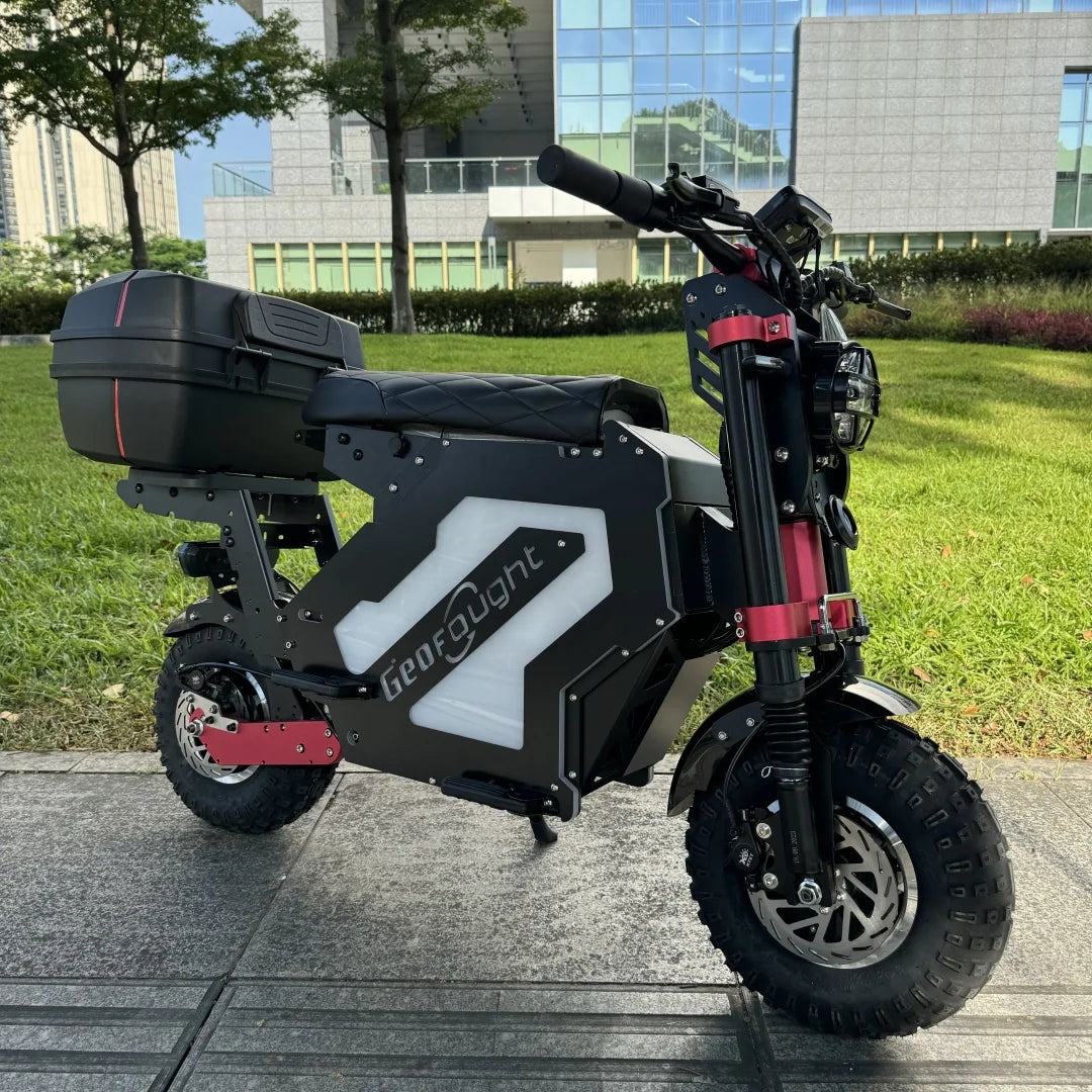 Electric scooter with a visible brand logo on a paved area with grass and buildings in the background
