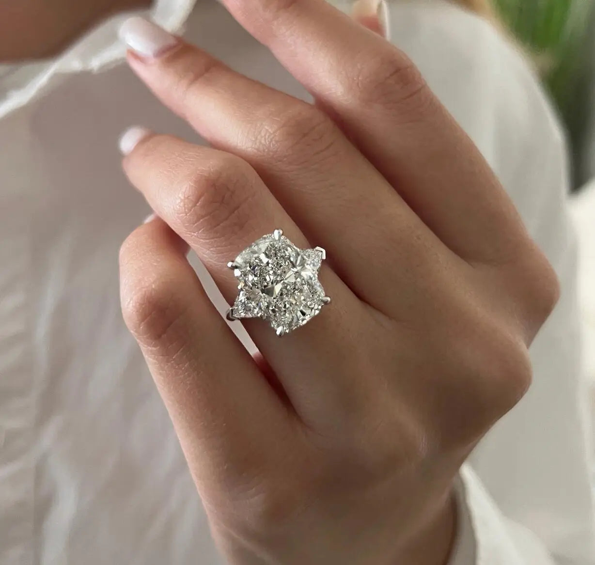 Close-up of a hand wearing a diamond ring with a blurred background
